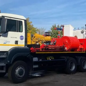 Large utility truck with mounted industrial equipment in a parking lot.