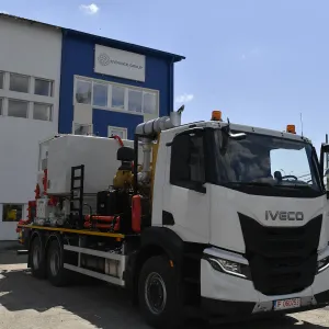 Large white Iveco utility truck parked outside an industrial building on a sunny day.